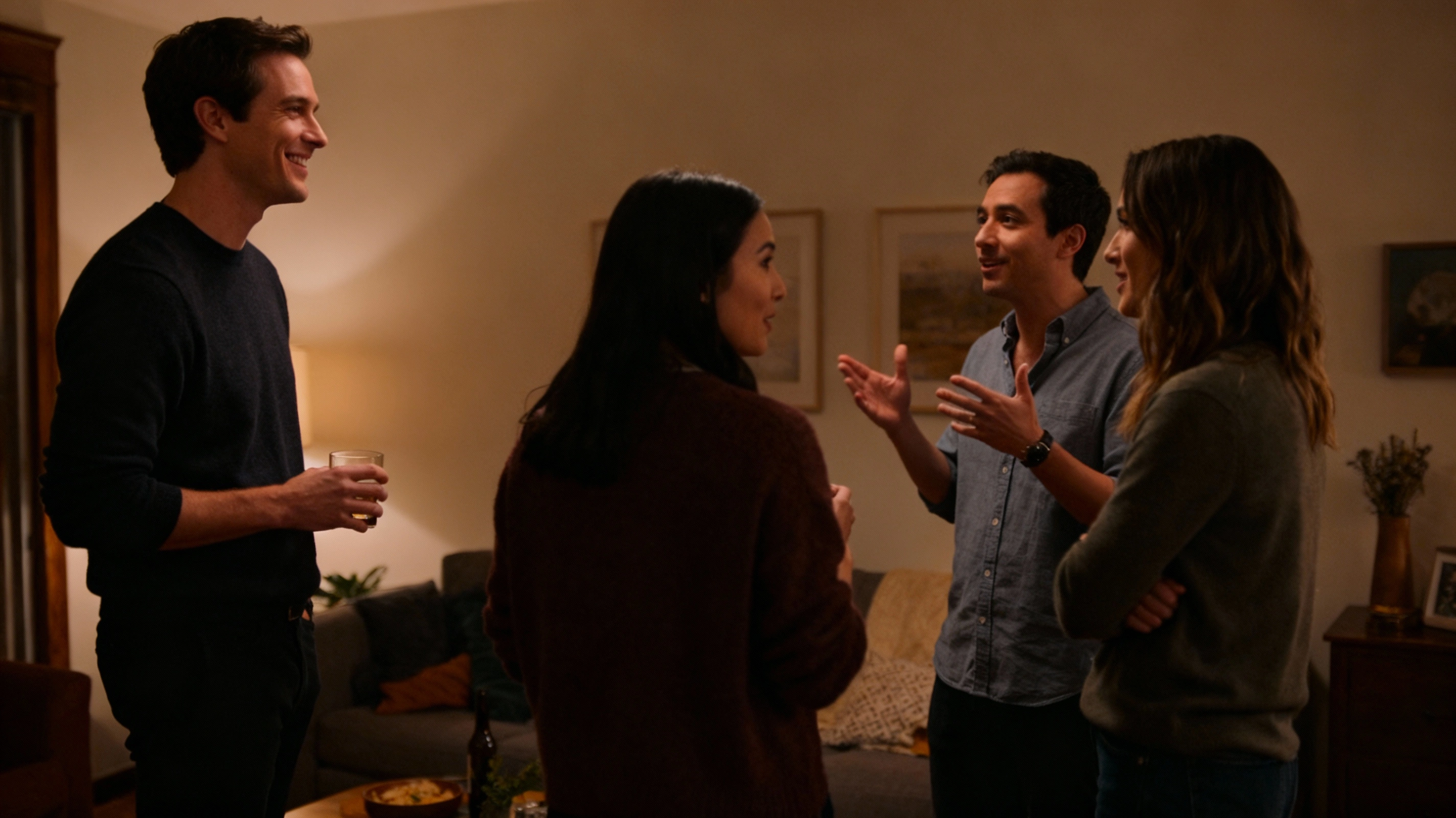 Joining small groups as an introvert at parties small group talking at a casual house party, introvert guy listening and smiling at the edge of the circle